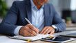 © Kateryna - Corporate professional writing important notes in notebook at organized office desk with laptop tablet and business paperwork visible for meeting preparation business notes not