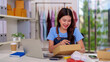 © snowing12 - Asian female entrepreneur efficiently packing clothing orders for her thriving online store from a modern home office managing her small business success