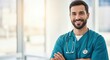 © Sabbir - Smiling male healthcare professional with stethoscope and scrubs confidently looking at the camera in a bright hospital setting