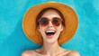 © Babb - A cheerful woman lies on a colorful beach towel, wearing a stylish sun hat and sunglasses. She beams with happiness under bright sunlight, enjoying her relaxing day outdoors.