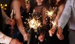© New Africa - Friends celebrating New Year with sparklers and wine glasses indoors, closeup