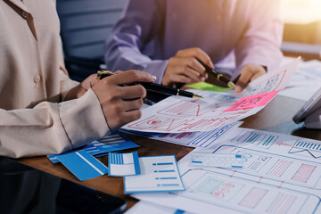Close up ux developer and ui designer brainstorming about mobile app interface wireframe design on table with customer breif and color code at modern office.Creative digital development agency.