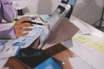 Close up ux developer and ui designer brainstorming about mobile app interface wireframe design on table with customer breif and color code at modern office.Creative digital development agency.