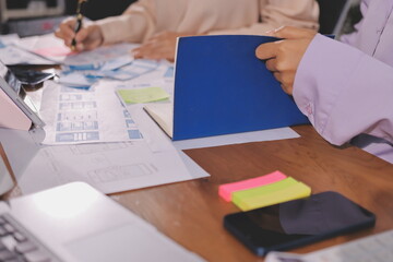 Close up ux developer and ui designer brainstorming about mobile app interface wireframe design on table with customer breif and color code at modern office.Creative digital development agency.