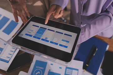 Close up ux developer and ui designer brainstorming about mobile app interface wireframe design on table with customer breif and color code at modern office.Creative digital development agency.