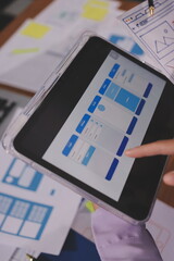 Close up ux developer and ui designer brainstorming about mobile app interface wireframe design on table with customer breif and color code at modern office.Creative digital development agency.