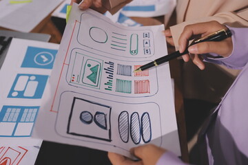 Close up ux developer and ui designer brainstorming about mobile app interface wireframe design on table with customer breif and color code at modern office.Creative digital development agency.