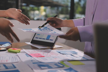 Close up ux developer and ui designer brainstorming about mobile app interface wireframe design on table with customer breif and color code at modern office.Creative digital development agency.