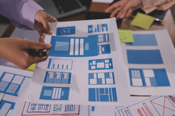 Close up ux developer and ui designer brainstorming about mobile app interface wireframe design on table with customer breif and color code at modern office.Creative digital development agency.