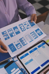 Close up ux developer and ui designer brainstorming about mobile app interface wireframe design on table with customer breif and color code at modern office.Creative digital development agency.