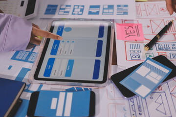 Close up ux developer and ui designer brainstorming about mobile app interface wireframe design on table with customer breif and color code at modern office.Creative digital development agency.