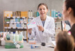 © JackF - Friendly young woman apothecary showing pills to mom with little girl in drugstore