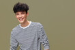 © SHOTPRIME STUDIO - smiling man with curly hair wearing striped shirt posing against beige background, happy expression, casual style, youthful and energetic mood
