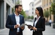 © zhao - Businessman holding coffee and tablet talking to businesswoman outdoors. High quality