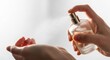 © Meow Creations - Close up of a woman hand spraying delicate floral perfume from a glass bottle onto her wrist