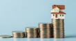 © Kiki - Small House Model Placed on Top of Stacked Coins Showing Upward Trend in Property Value and Investment Growth Concept