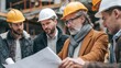 © CStock - Five construction workers discuss plans on-site, showcasing teamwork and collaboration in a professional environment.