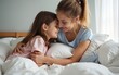 © David - Portrait of loving mum hug little daughter sit in bed feels happy spend time together. Carefree motherhood, new mom for grateful adopted kid, good morning, fun at home, Mother or Child day celebration