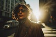 Woman wearing fringe leather jacket walking sunlit city street full figure wide shot.