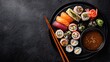© Tombol - Assorted sushi and sashimi arranged on a dark platter with chopsticks and soy sauce, set against a dark background