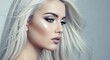 © AK_KADER - Ethereal winter beauty portrait of a young woman with silver icy glitter makeup and flowing platinum blonde hair against a soft grey background symbolizing a frost fairy princess