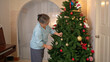 © Wosunan - On a holiday, an elderly woman enjoys decoration Christmas tree and playing the piano at home