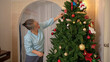 © Wosunan - On a holiday, an elderly woman enjoys decoration Christmas tree and playing the piano at home