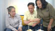 © Wosunan - Happy elderly man blowing out birthday candles surrounded by friends