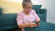 © Wosunan - On a holiday, an elderly woman relaxes with a smartphone on the sofa