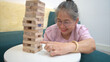 © Wosunan - On a holiday, an elderly man enjoys jenga game in living room of house