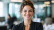 © CStock - A confident woman smiling in a modern office environment, showcasing professionalism and positivity.