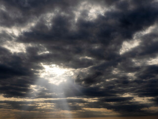 Wall Mural - Dark and dramatic cloudy sky with sun beams. Nature background for design.