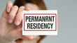© Pawel - A person is holding a card that says Permanent Residency