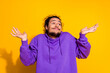 © deagreez - Confused man in a purple hoodie expressing a casual shrug gesture with a cheerful mood on a bright yellow background