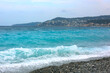 Beautiful view of wavy sea, city and pebbles on beach