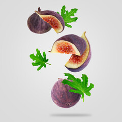 Wall Mural - Fresh sweet figs and green leaves falling against white background