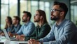 © Viktor - Diverse group of professionals attend important business meeting in bright, modern office setting. Focused colleagues sit at conference table, listening intently to speaker. Young people learn,