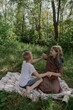 © looking2thesky - A young brother and sister enjoy a picnic together in a sunny park, sharing authentic moments of sibling bonding and simple outdoor joy. Pure, unfiltered family happiness