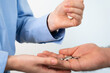 © SVITLANA - Close-up of a business persons hand giving coins to another, concept of change, savings, or small payments.