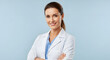 © leonardo - Smiling female doctor with folded arms, isolated on light blue background.