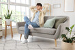 © Pixel-Shot - Dreaming young man sitting on sofa at home