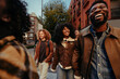 © bernardbodo - Happy multiracial friends walking and laughing in the city