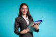 © Kawee - Portrait of Asian businesswoman standing in isolated blue background.