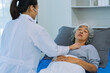 © ArLawKa - Doctor is examining elderly female patient in ward while doctor is checking her condition in recovery room. Medical and healthcare concept.