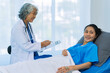 © ArLawKa - Elderly female doctor and Asian female patient are discussing something while sitting on hospital bed. Medical consultation concept.