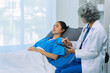 © ArLawKa - Elderly female doctor and Asian female patient are discussing something while sitting on hospital bed. Medical consultation concept.
