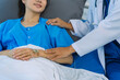 © ArLawKa - Elderly female doctor and Asian female patient are discussing something while sitting on hospital bed. Medical consultation concept.
