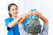 © ArLawKa - Young nurse trains elderly woman to exercise her arm during therapy and rehabilitation in her living room at home. Physical therapist.