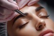 © Vitalii Shkurko - A skilled technician is shaping brows with tweezers while a client relaxes. The scene highlights the focus on precision and beauty care in a serene atmosphere