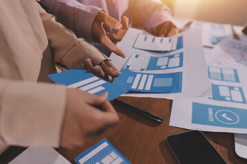 Close up ux developer and ui designer brainstorming about mobile app interface wireframe design on table with customer breif and color code at modern office.Creative digital development agency.